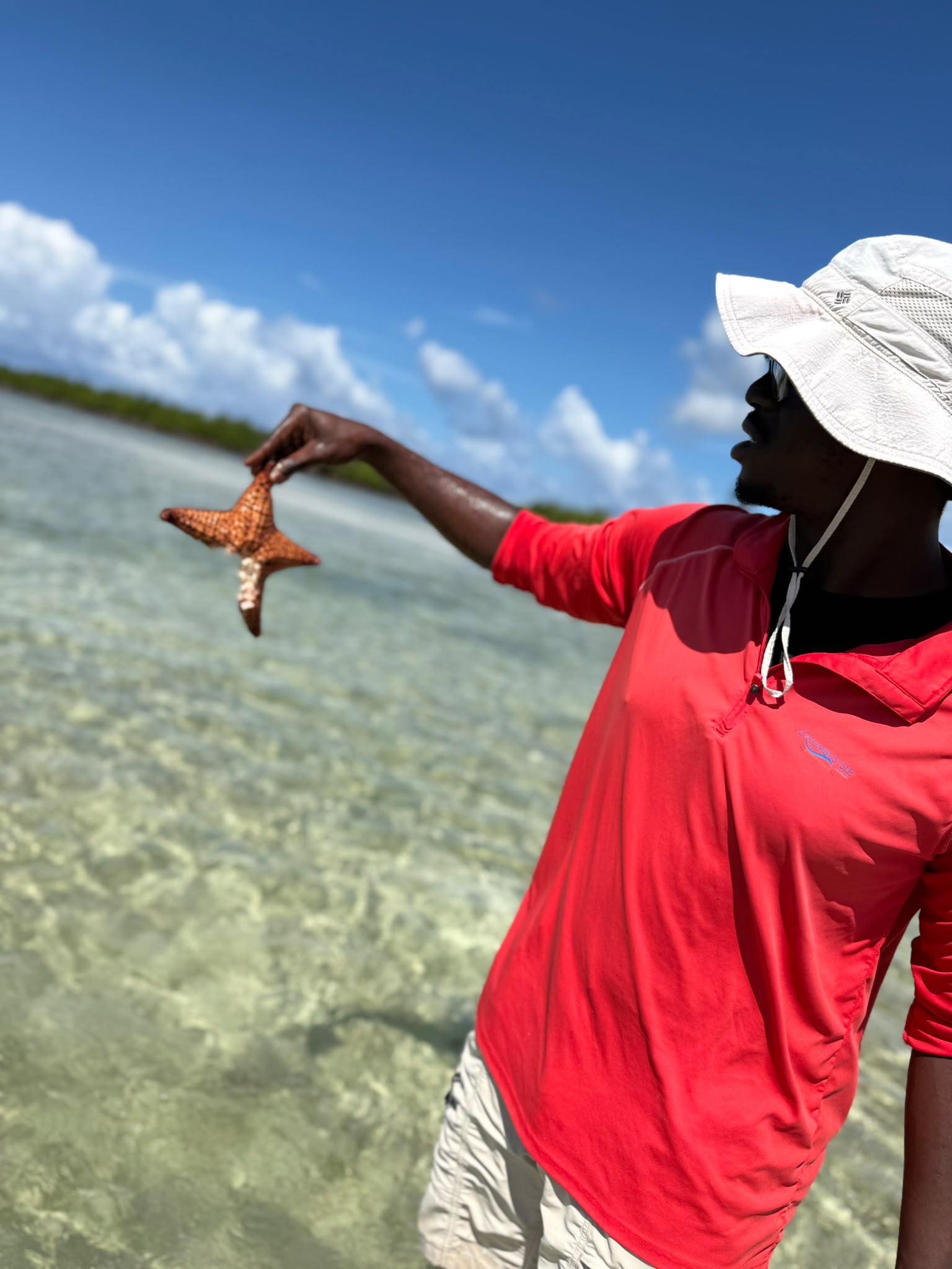 Local guide holding a starfish above clear shallow water